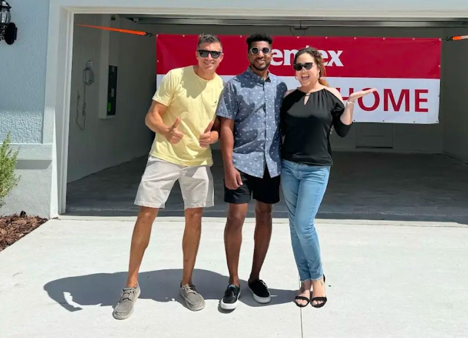 Robert with a couple under a Centex welcome-home banner