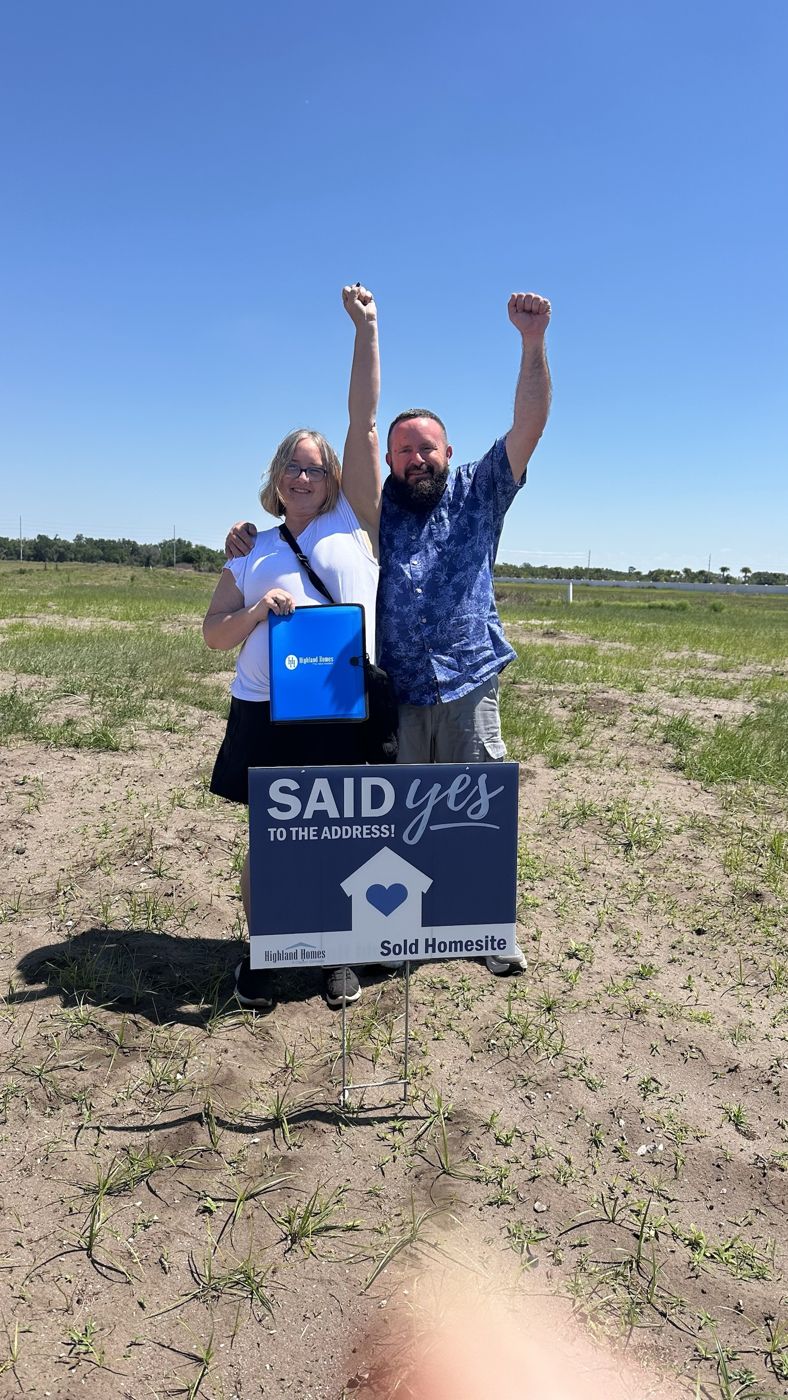 A couple at their Highland Homes homesite with a Said Yes to the Address sign