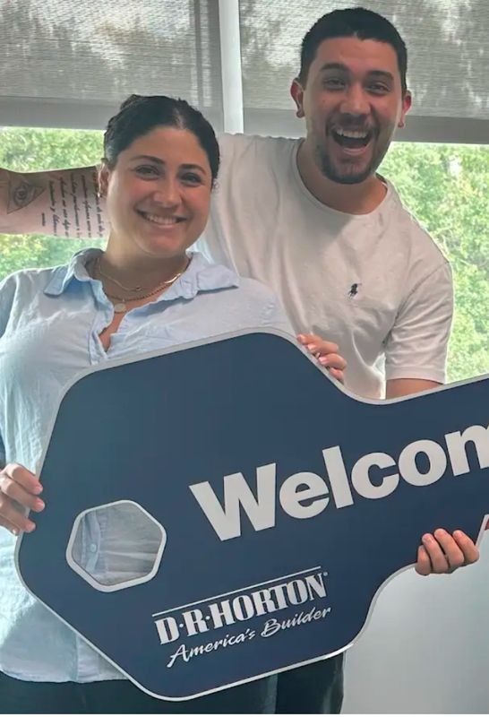 New homeowners holding a giant D.R. Horton welcome key