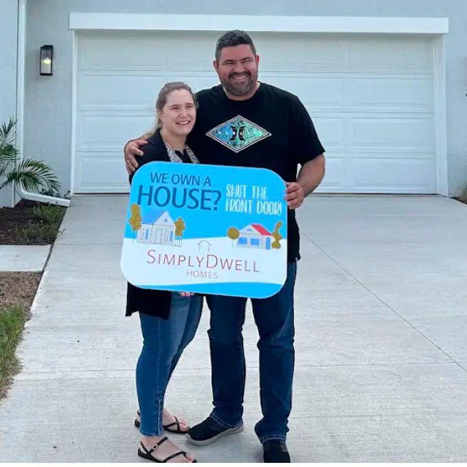 New SimplyDwell homeowners with a We Own a House sign