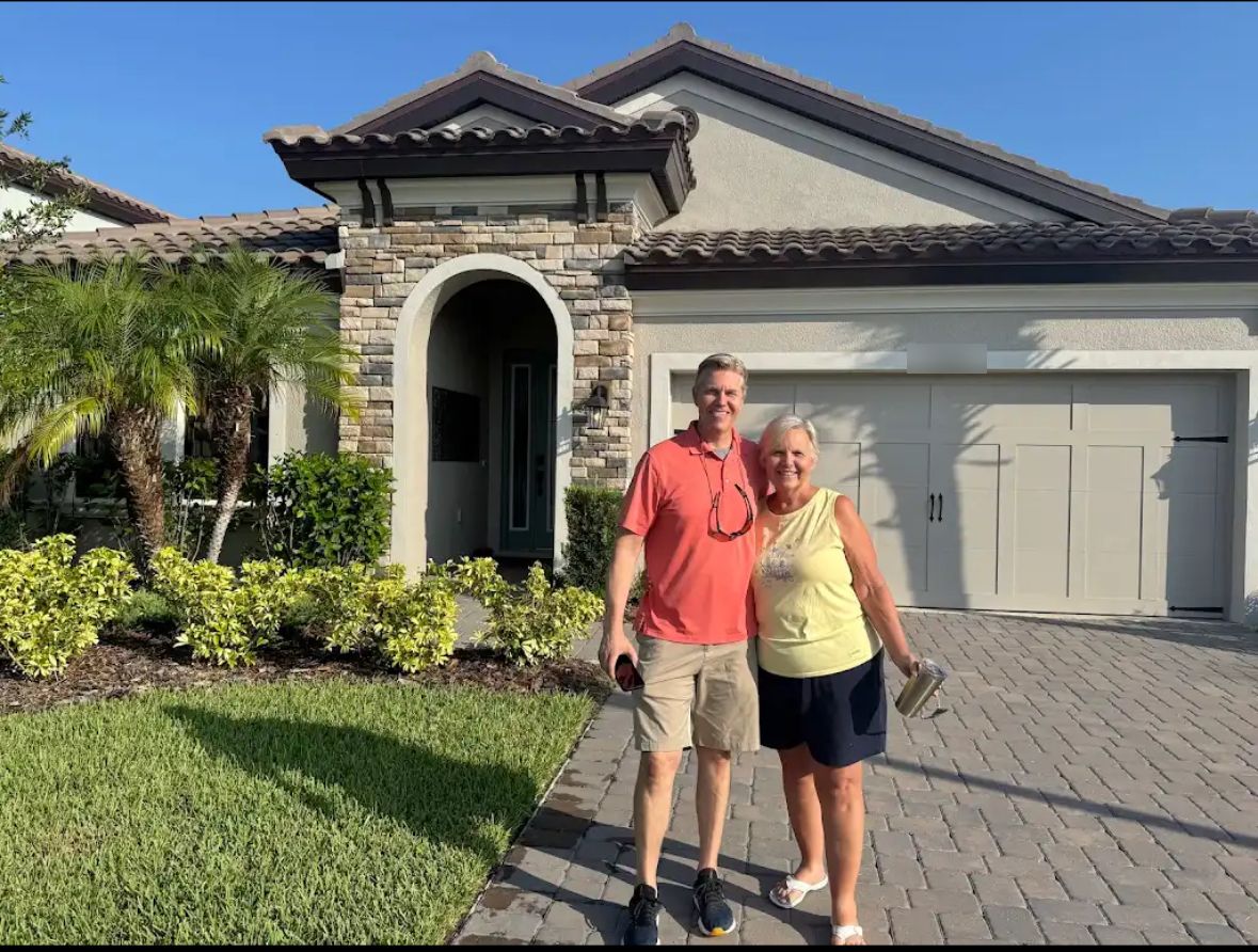 Robert with a happy homeowner in front of her new tile-roof home